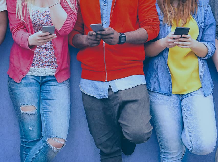 Abbildung von drei Jugendlichen mit Smartphones im Anschnitt